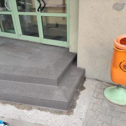 Nowo ułożone ciemnoszare płytki ceramiczne na schodach wejściowych.